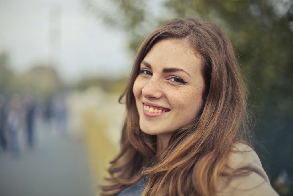 A young woman smiling warmly with a blurred outdoor background in Budapest.